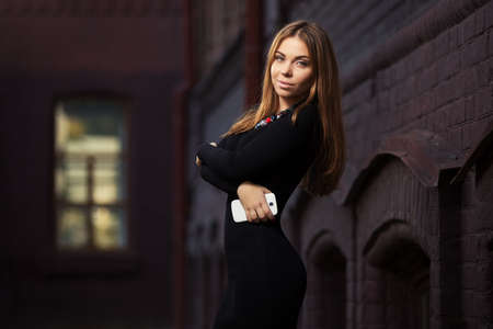 Young fashion woman in black dress with smart phone outdoorの写真素材