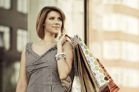 Happy young woman with shopping bags against mall windowの写真素材