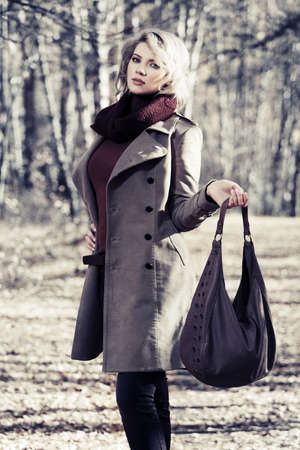 Young blond fashion woman walking in autumn forestの写真素材