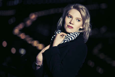 Young blond fashion woman walking on the night city streetの写真素材