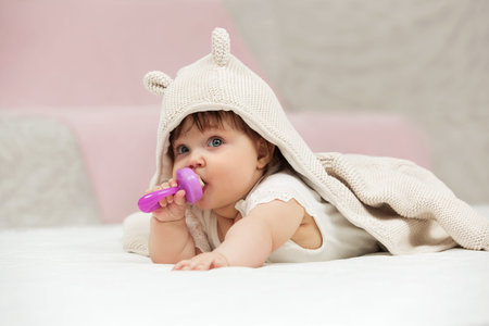 Portrait of baby girl playing with toy on blanket at home