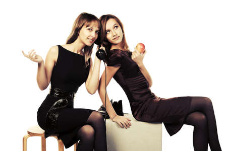Two happy young fashion women calling on retro phoneの写真素材