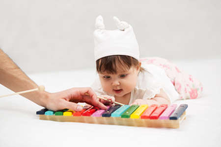 Baby girl playing with xylophone toy on blanket at homeの写真素材