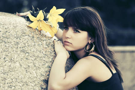 Sad young woman with a flowers on city streetの写真素材