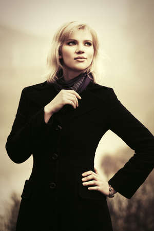 Young fashion woman in black coat walking in a fog outdoorの写真素材