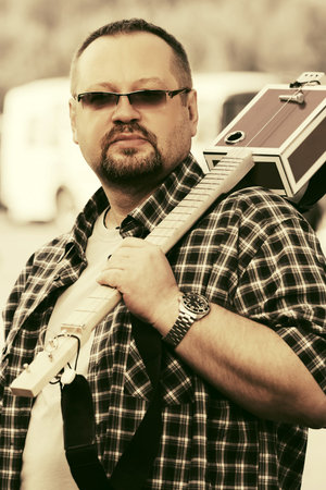 Man with a cigar box guitar walking in city street