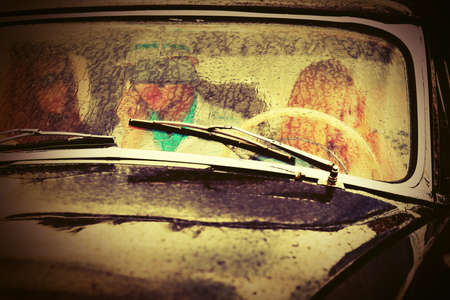 Young people driving vintage car in the rainの写真素材