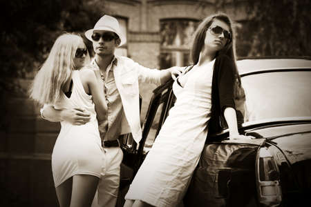 Happy young fashion man and women next to vintage carの写真素材