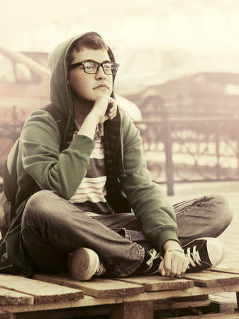 Portrait of young fashion man sitting on city streetの写真素材