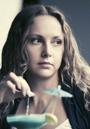 Sad beautiful young woman with cocktail at restaurantの写真素材