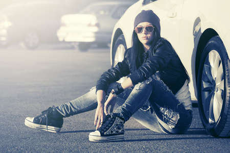 Young fashion woman in sunglasses sitting next to her carの写真素材
