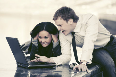 Young business couple using laptop outdoor の写真素材
