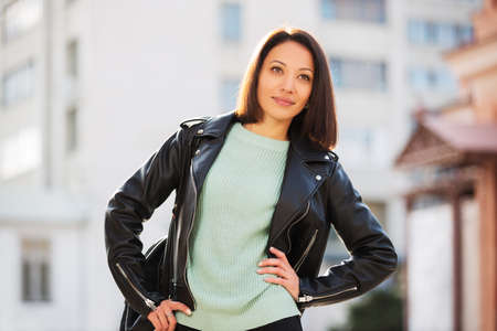 Young fashion woman walking in city street Stylish female model in black leather jacket outdoorの写真素材