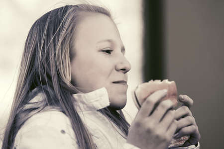 Happy teen girl eating a burgerの写真素材