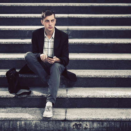Young handsome business man using smart phone on the stepsの写真素材