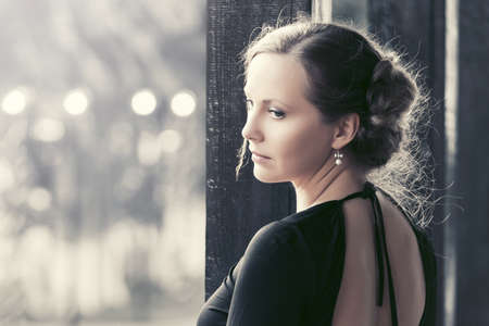 Sad beautiful fashion woman in black dress in a city streetの写真素材