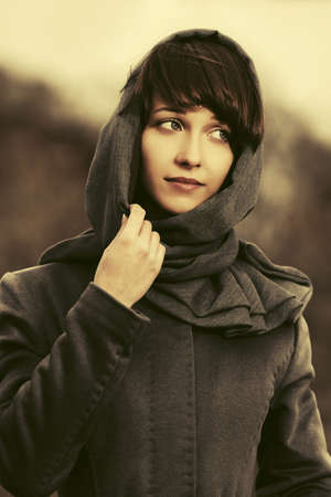 Sad young fashion woman in classic coat and headscarf の写真素材