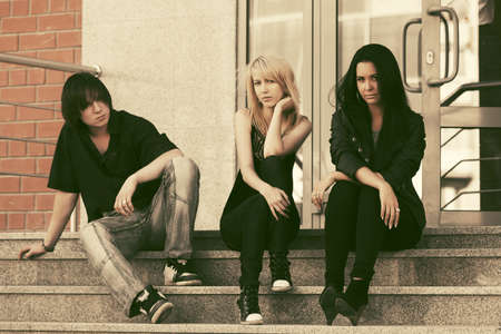 Young fashion men and women sitting on the steps. Stylish trendy male and female models outdoorの写真素材