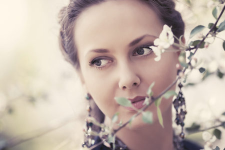 Happy beautiful woman walking in a spring blooming garden Stylish fashion model with braid hairstyle...