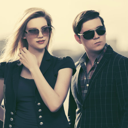 Young fashion man and woman in sunglasses walking in city street