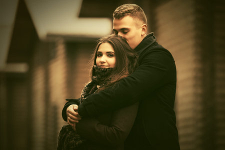 Happy young fashion couple in love embracing outdoor Stylish man and woman in classic coats