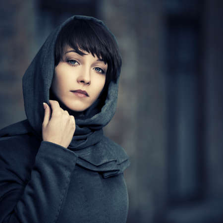 Sad young fashion woman walking on city street Stylish female model in gray classic coat and headscarf の写真素材