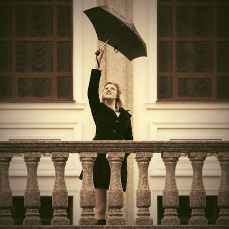 Young fashion woman with umbrella walking on city street Stylish female model wearing classic black coatの写真素材