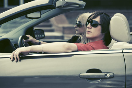Happy young couple driving convertible car