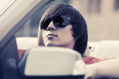Young handsome man in sunglasses driving convertible car