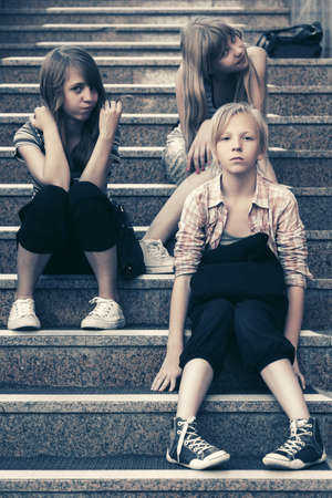 Group of happy fashion teenage girls sitting on stepsの写真素材
