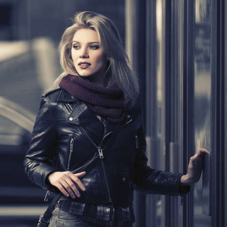 Young fashion blonde woman wearing black leather jacket at the mall doorwayの写真素材