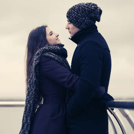Happy young fashion couple in love embracing outdoor Stylish man and woman wearing classic coats beanie and scarfの写真素材
