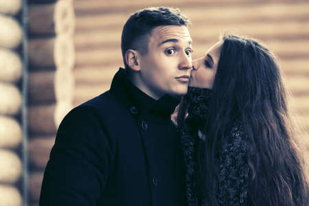 Happy young fashion couple in love kissing on street  Stylish man and woman in classic coatsの写真素材