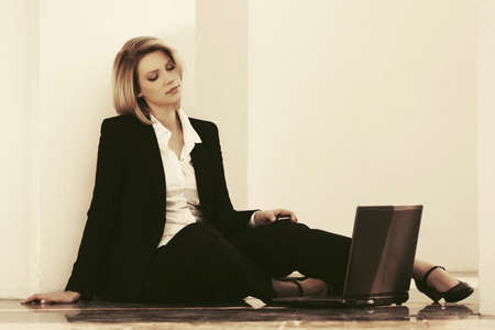 Young business woman with laptop sitting at the wall Stylish fashion model in black suitの写真素材