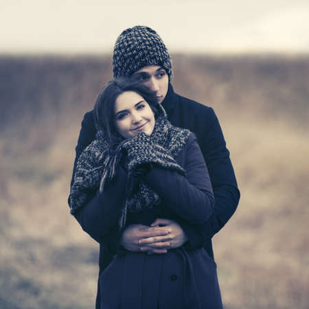 Happy young fashion couple in love embracing outdoor Stylish man and woman in classic coats beanie and scarfの写真素材