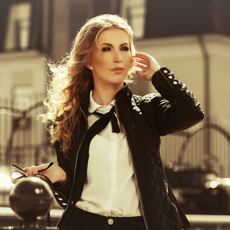 Young fashion blonde business woman walking on city street Stylish female model in black jacket and white shirtの写真素材