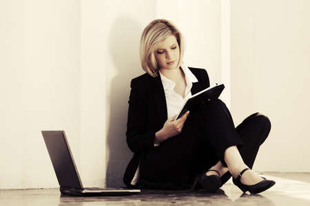 Young business woman with laptop sitting at the wall Stylish fashion model in black suitの写真素材