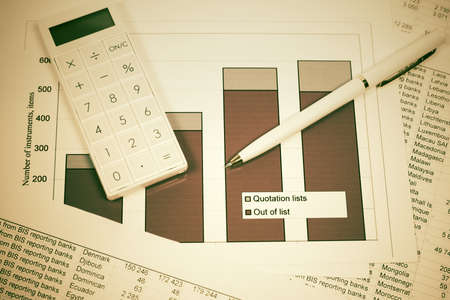 Financial accounting stock market graphs and charts analysis pen and calculator on balance sheetsの写真素材