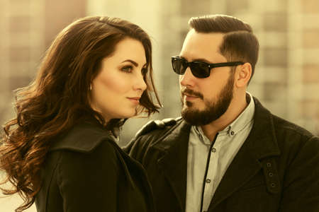 Happy young fashion couple walking on city street Stylish man and woman in classic coatsの写真素材