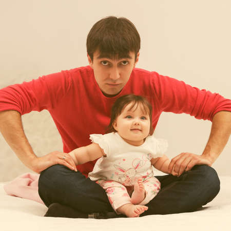 Happy young father and baby girl sitting on blanket at homeの写真素材