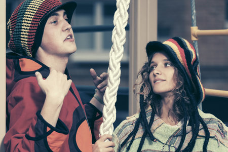 Happy young fashion hipster couple on the playground Stylish trendy man and woman in hooded...