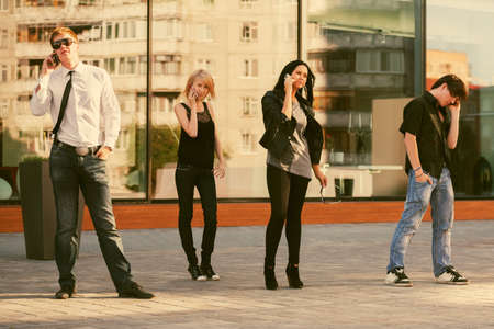 Young fashion people calling on cell phones on city street Stylish trendy men and womenの写真素材