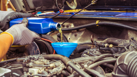 mechanic replacing new oil engine and pouring to car in service shopの写真素材