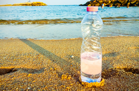 water bottle on beach with blue sae backgroundの写真素材