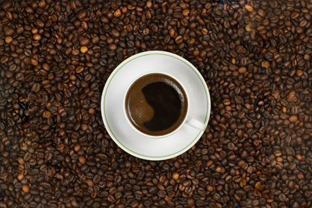 a cup of natural ground coffee with foam on coffee beans, top view