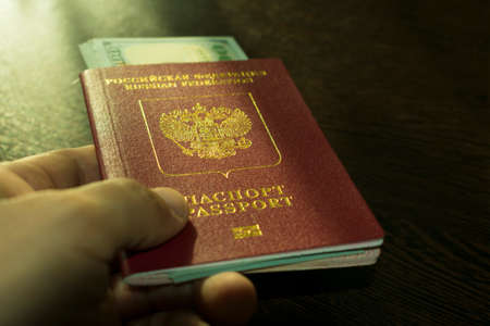 Russian foreign passport with inside dollars in the outstretched handの写真素材