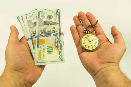 pocket watch with a chain in his right hand and American hundred dollar bills in his left handの写真素材