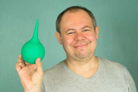 a man in a gray T-shirt of a paramedic with a smile proposes to make an enema a patientの写真素材