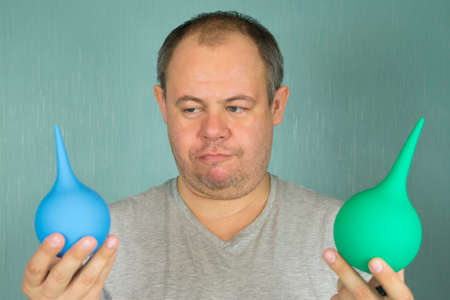 a guy chooses between a large and a small enema for a cleansing procedureの写真素材