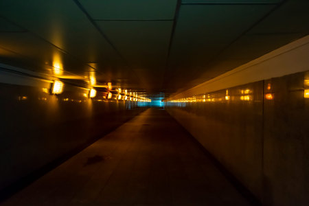 a deserted underground passage illuminated by yellow lanterns and puddles on the asphalt